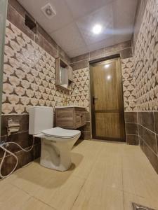 ein Badezimmer mit einem WC und einer Holztür in der Unterkunft WADl RUM DESERT CAMP in Wadi Rum