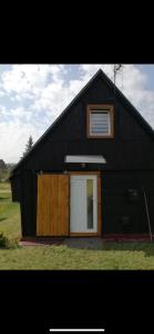 eine schwarze Scheune mit einer weißen Tür und einem Fenster in der Unterkunft Chata Dominika in Dolná Strehová