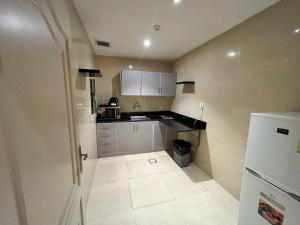 a small kitchen with white cabinets and a refrigerator at Holiday Plus Al Salamh- هوليداي بلس السلامه in Jeddah