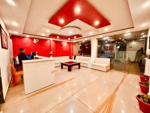 Eine Lobby mit roten Wänden und ein Mann am Tresen. in der Unterkunft Hotel The Pacific Paradise in Haridwar