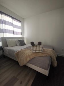 een slaapkamer met een bed met een deken en een raam bij Beautiful, 4brd-3bthTownhome 7mins to Lakeshore in Barrie