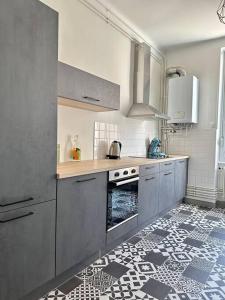 cocina con armarios grises y suelo de baldosa en Chez Delphine, en Bourg-en-Bresse