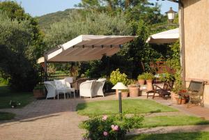 une terrasse avec des tables et des chaises sous un parasol dans l'établissement Podere Turicchio, à Orbetello