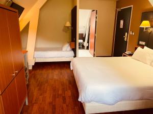 um quarto de hotel com duas camas e um corredor em Logis Hôtel La Brèche de Roland em Gèdre