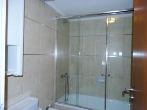 a shower with a glass door in a bathroom at Departamentos Leloir in Neuquén