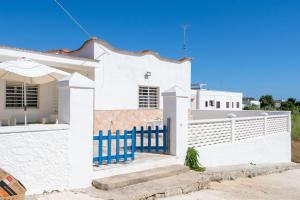una casa blanca con una valla azul en Villetta Rosa House 100 meters from the blue sea, en San Pietro in Bevagna