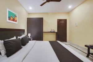 a bedroom with a large white bed with black pillows at Super OYO Anuguna Tulasi Grand Near JNTU University Hyderabad in Kukatpalli