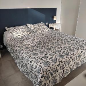 een slaapkamer met een bed met een zwart-wit dekbed bij La maison sous les pins in Saint-Laurent-dʼAigouze