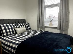 a bedroom with a black and white bed and a window at Large Cosy Home - B'ham, Solihull, NEC, M42, HS2 in Birmingham