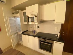 a kitchen with white cabinets and a sink and a microwave at إطلالة هوانا in Ma‘mūrah