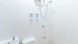 a white bathroom with a shower and a sink at RedDoorz at Casa Buena Dormitel Davao City in Davao City
