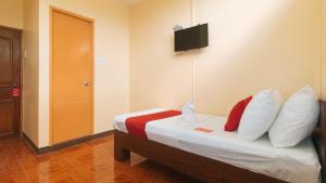 1 dormitorio con 1 cama con almohadas y TV en la pared en RedDoorz at Casa Buena Dormitel Davao City en Davao