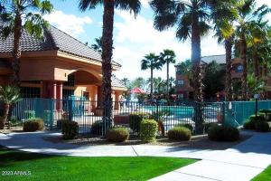 uma cerca em frente a uma casa com palmeiras em Sun City Grand Oasis: Luxury Condo Living in La Solana em Surprise