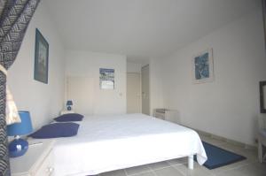 a white bedroom with a large white bed with blue pillows at Alamic in Grimaud