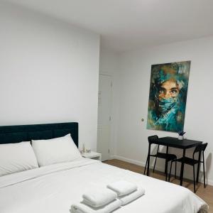 a bedroom with a white bed and a painting on the wall at Viva Apartments in Përmet