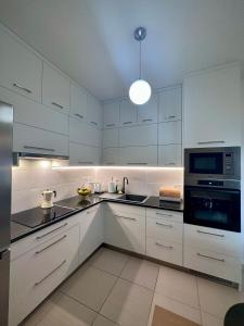La cuisine est équipée de placards blancs, d'un évier et d'un four micro-ondes. dans l'établissement White Coast Apartment, à Saranda