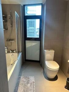 a bathroom with a toilet and a tub and a window at Stylist 2 Bedroom Apartment in Central London in London