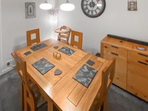 a wooden table with chairs and a clock on the wall at Elizabeth Lodge in Alford
