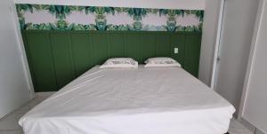 a bed in a green room with two pillows on it at Iguassu Jungle pousada in Foz do Iguaçu