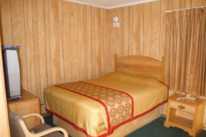 Bel-Air Motel في Alice: غرفة نوم صغيرة بها سرير وكرسي