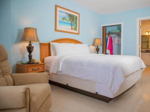 um quarto com uma grande cama branca e uma cadeira em Princess Vegas Hotel & Casino em Corozal