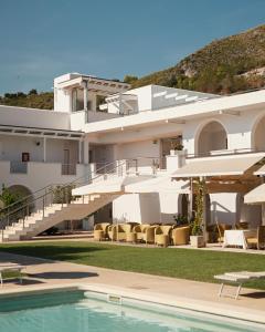 een groot wit gebouw met een zwembad en stoelen bij Hotel Grotta Di Tiberio in Sperlonga