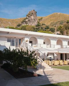 een groot wit gebouw met een berg op de achtergrond bij Hotel Grotta Di Tiberio in Sperlonga