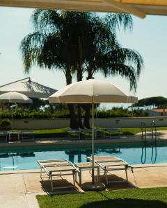 twee stoelen en een parasol naast een zwembad bij Hotel Grotta Di Tiberio in Sperlonga