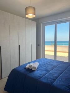 - une chambre avec un lit bleu et 2 serviettes de toilette dans l'établissement Attico una finestra sulle Isole Eolie, à Brolo