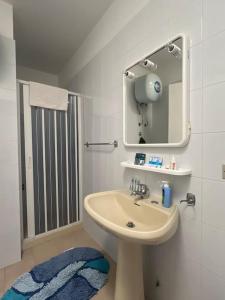 La salle de bains blanche est pourvue d'un lavabo et d'un miroir. dans l'établissement Attico una finestra sulle Isole Eolie, à Brolo