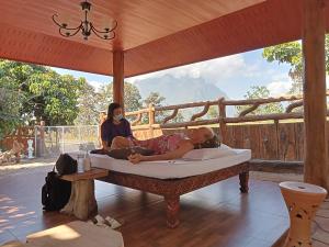 two women laying on a bed under a canopy at PJ Garden Home (Chiang Dao) in Chiang Dao