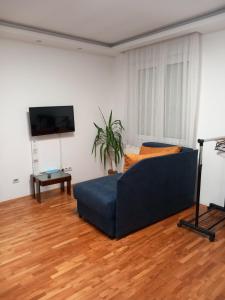 a living room with a blue couch and a television at Apartmani Pause in Niš