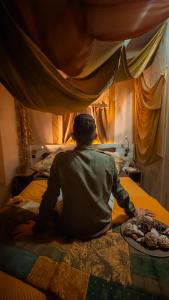 un homme assis sur un lit avec une assiette de nourriture dans l'établissement Ciriga Sicily Glamping Resort, à Santa Maria Del Focallo