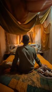 a man sitting on a bed with a plate of food at Ciriga Sicily Glamping Resort in Santa Maria Del Focallo