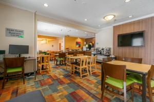 a hotel room with tables and chairs and a restaurant at Wingate by Wyndham Great Falls in Great Falls