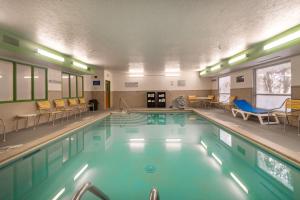 a swimming pool with chairs and chairs in a building at Wingate by Wyndham Great Falls in Great Falls