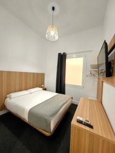 1 dormitorio con 1 cama, TV y mesa en Hostel Siesta & Go (Atocha), en Madrid