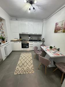 a kitchen with white cabinets and a table with chairs at The moon view in Bucharest