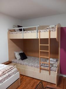 two bunk beds in a room with a ladder at Apartmani Pause in Niš