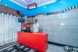 a man talking on a cell phone at a red counter at OYO Royal Inn Near Iskcon Temple Bangalore in Bangalore
