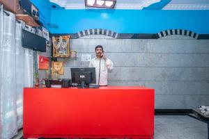 a man talking on a cell phone behind a red counter at OYO Royal Inn Near Iskcon Temple Bangalore in Bangalore