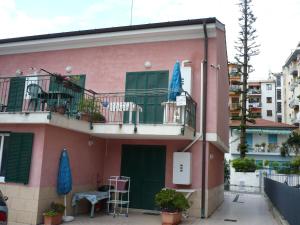 a pink house with a balcony and a table and a chair at Villamareblu in Ventimiglia