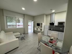 uma sala de estar com um sofá branco e uma mesa de vidro em Garden City Loft Nº2/2 em Córdoba