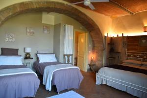 3 camas en una habitación con un arco en Agriturismo Poggio ai Legni, en Sovicille