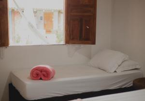una rosquilla rosa sentada encima de una cama en Casinhas da Serena - Casa cacau en Caraíva