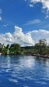 una piscina con cielo azul y nubes en Suítes Canaã, en Capitólio