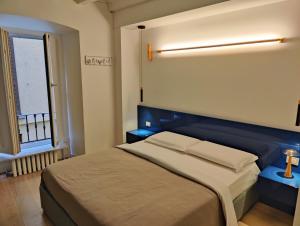 een slaapkamer met een bed met een blauw hoofdeinde en een raam bij Cozy Apartment Brera in Milaan