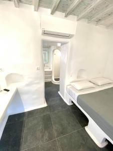 Habitación blanca con cama y escritorio. en MYKONOS VIBES AIRPORT STUDIOS AND APARTMENTS en Aggelika