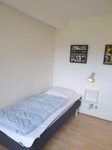 Cama en habitación con pared blanca en Stokrosen, en Åkirkeby