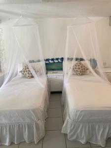 a bedroom with two beds with mosquito nets at Blue Bamboo cottage Marigot Bay. in Marigot Bay